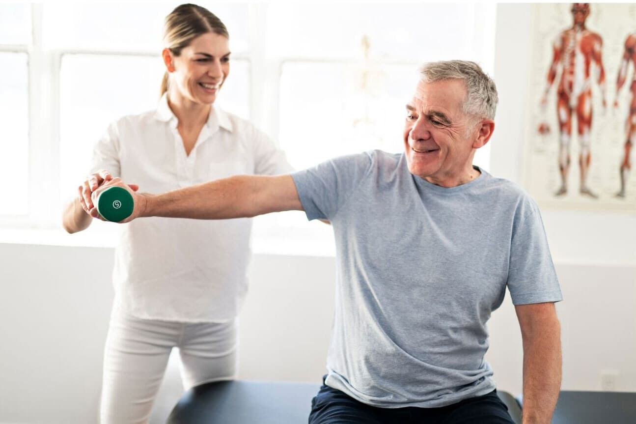 A physiotherapist helping a man with exercises and lift weight in his right hand