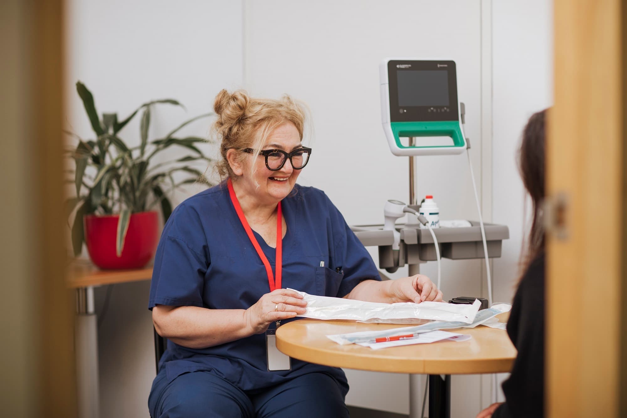 An MS Plus continence nurse seated in a consultation room talking to a client.