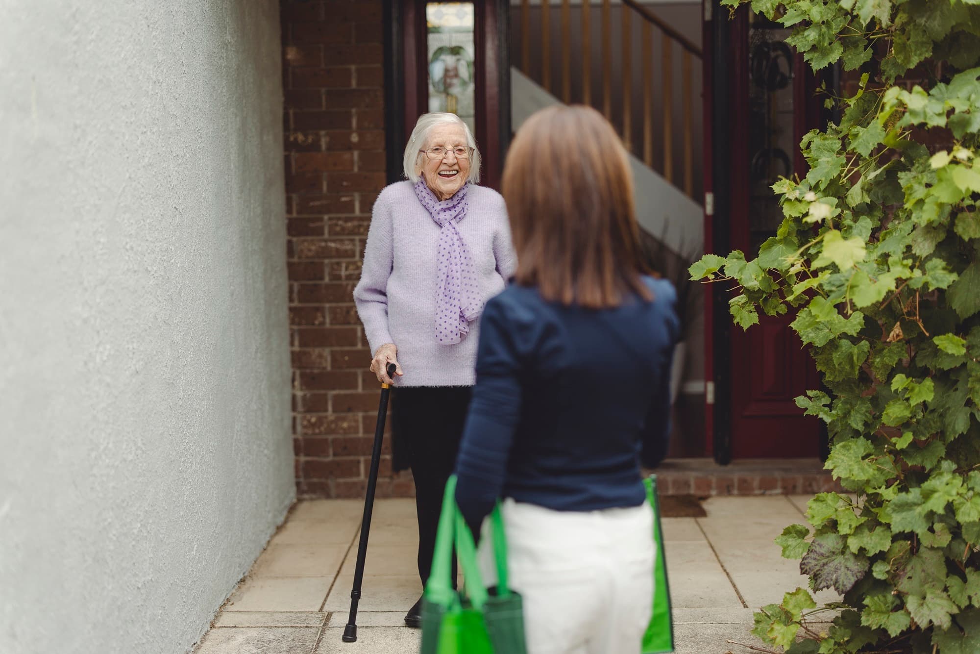 A volunteer visiting the home of an elderly woman to provide support.