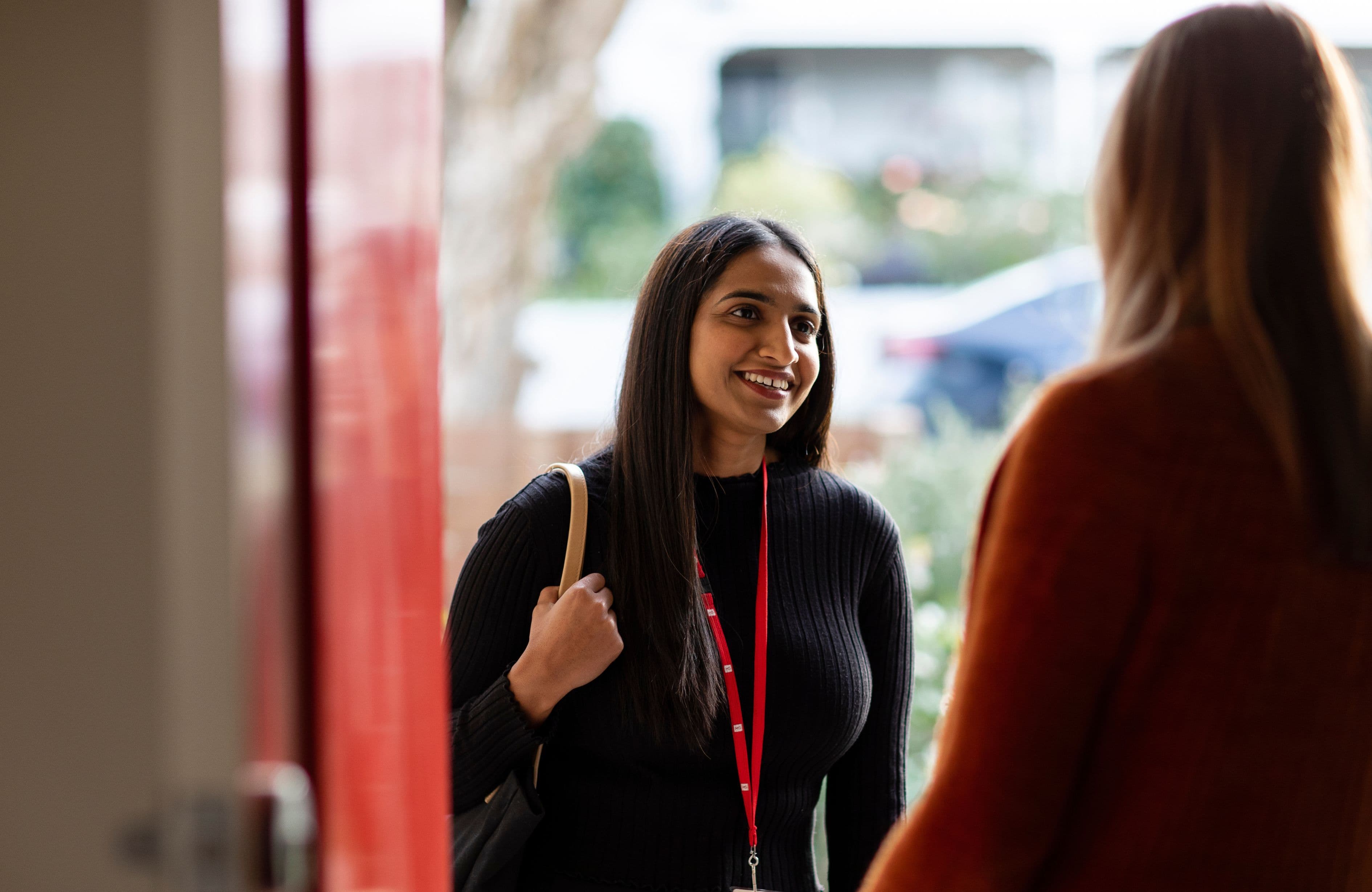 An MS Plus employee being greeted by a client at her front door.