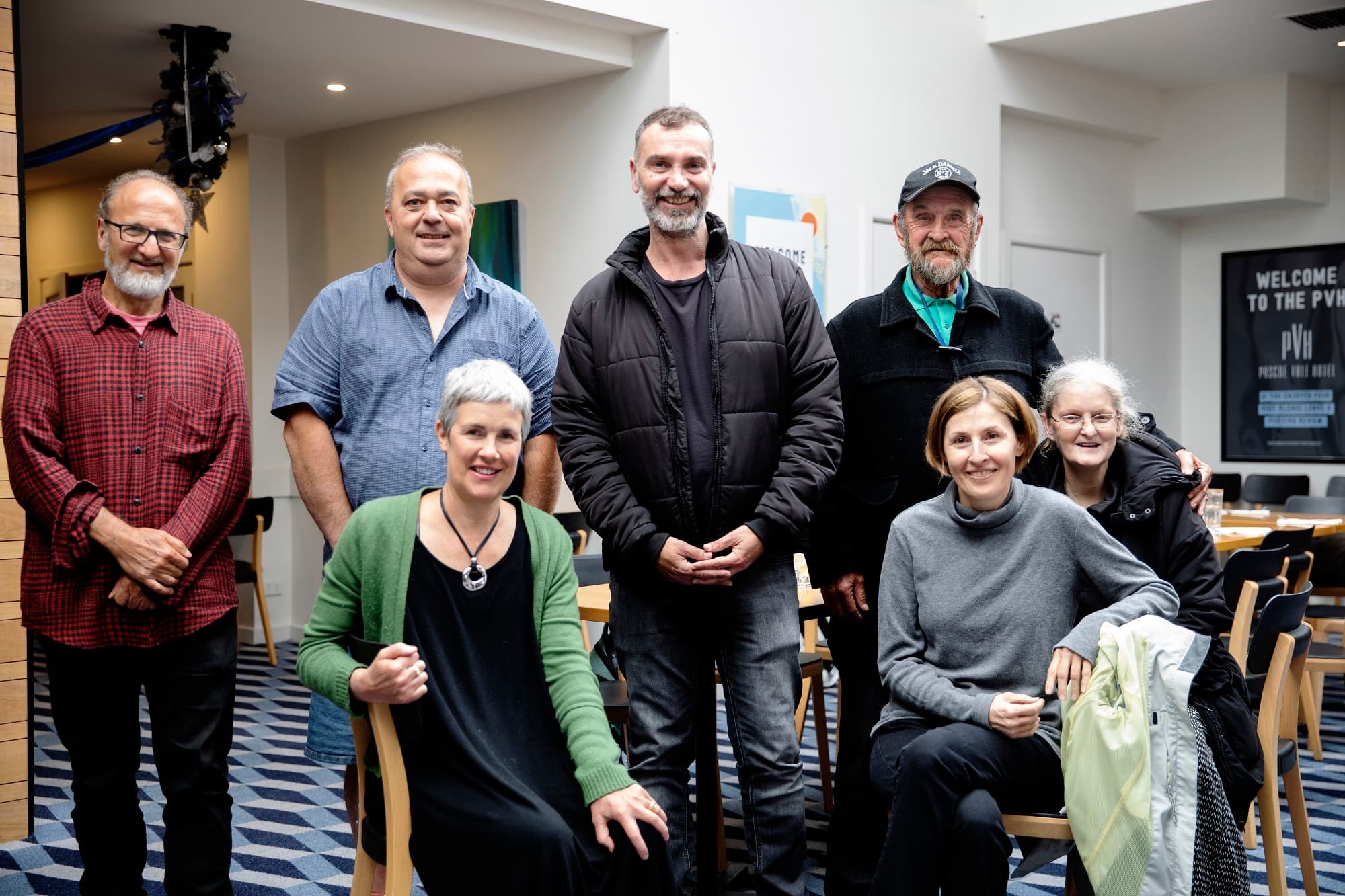 A group of people in peer support group smiling and posing for camera.