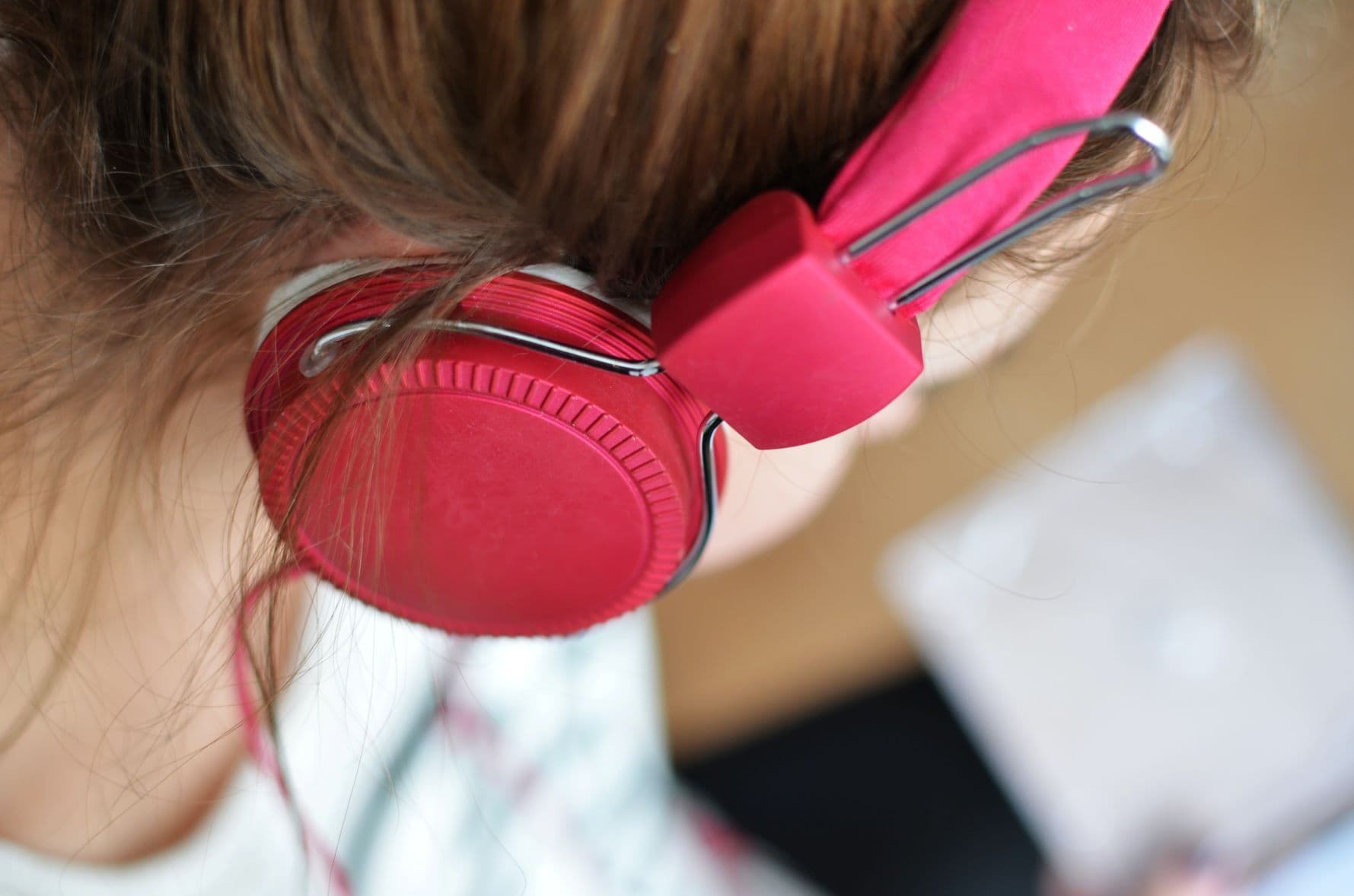 Close-up of a person listening to pink headphones.
