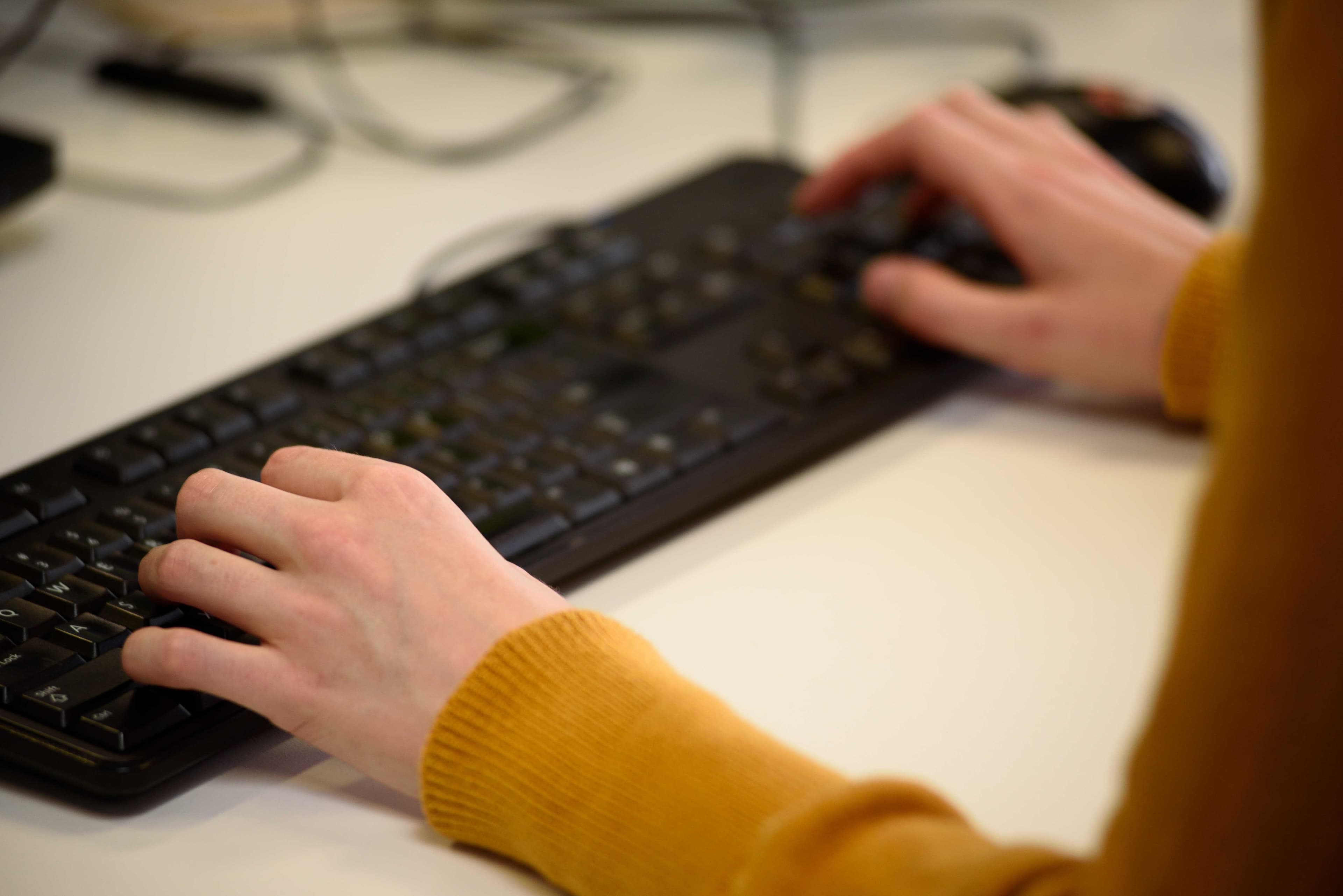 A close up of hands typing on a keyboard.
