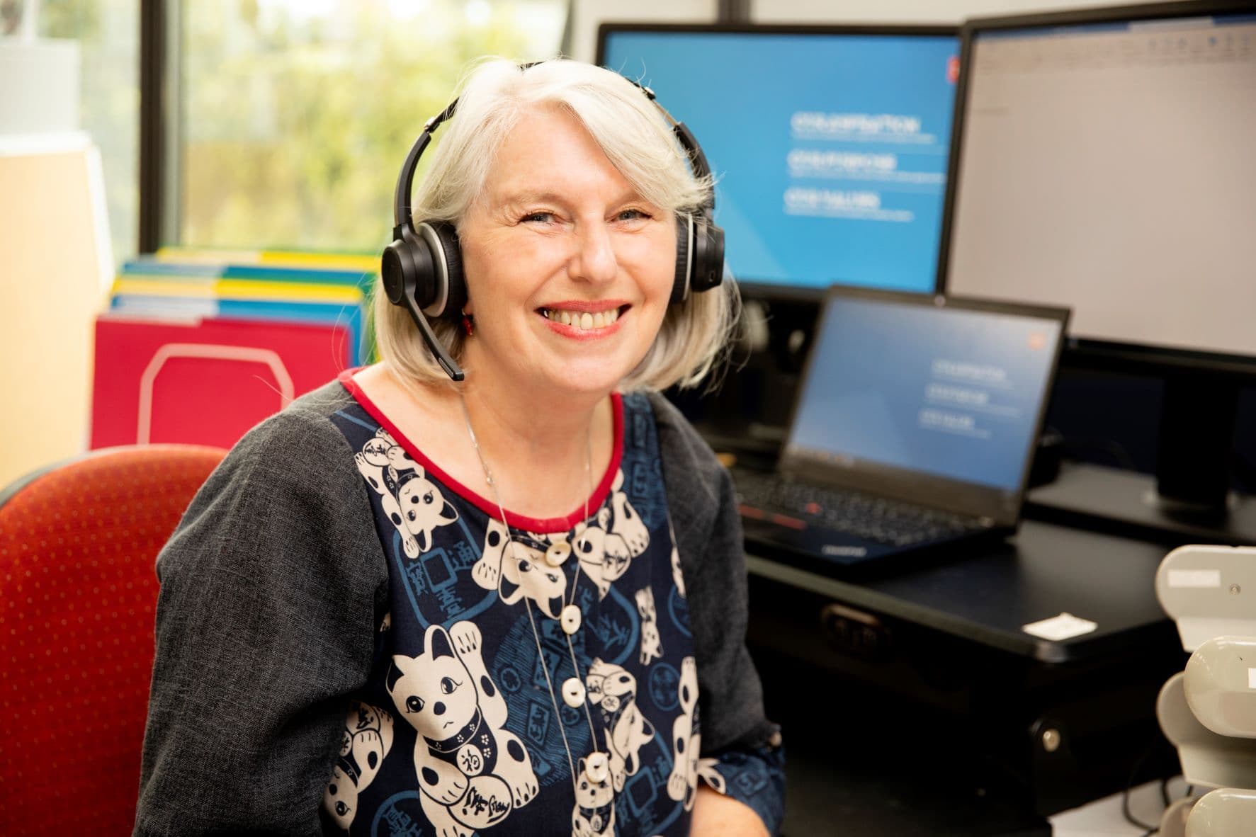 An MS Plus staff member seated at her desk wearing a headset.