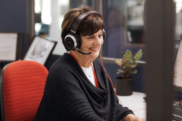 An MS Plus employee seated at her desk wearing a headset.
