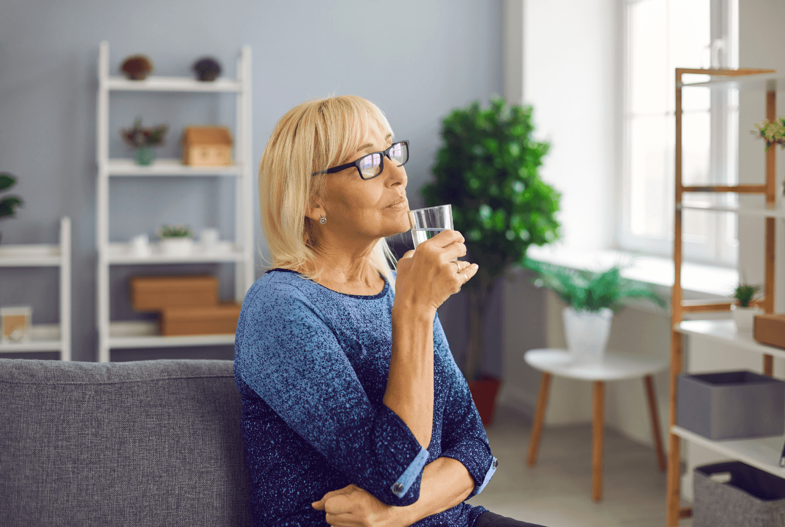 A woman seated on a couch holding a glass of water.