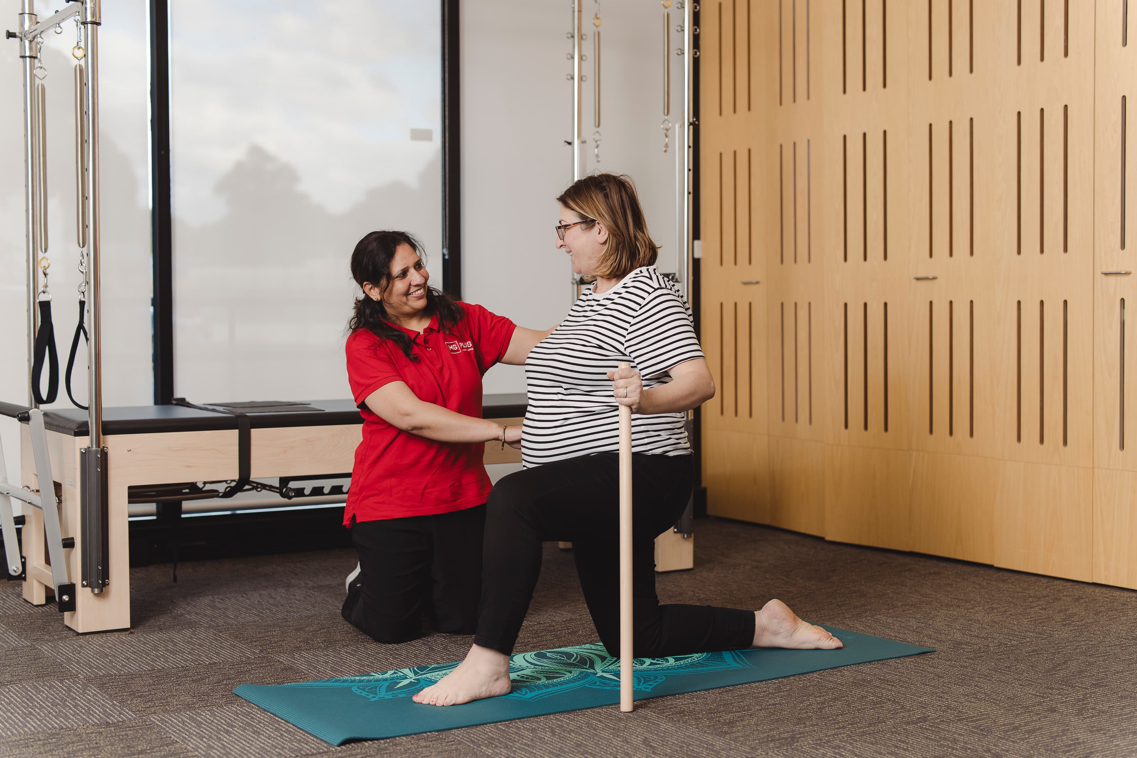 An Allied Health Assistant supporting a woman doing exercise.