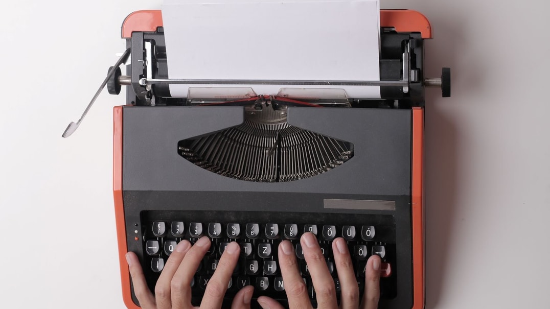 Hands on an orange typewriter