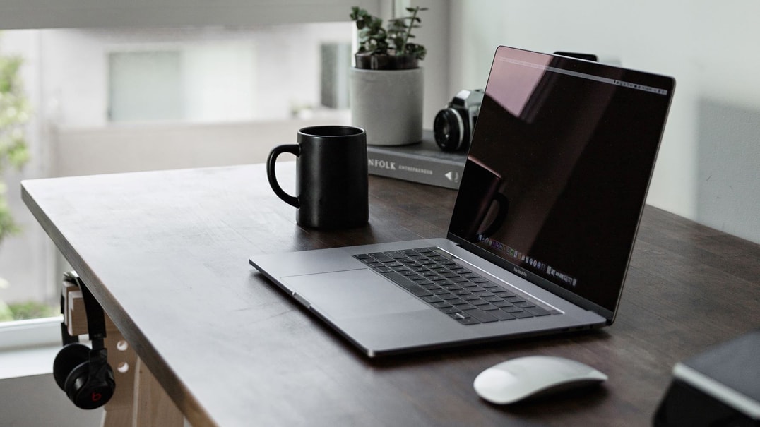 Laptop on wooden desk with coffee cup