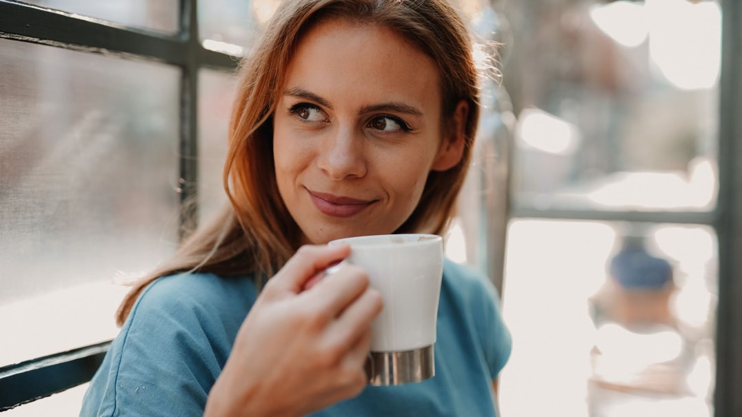 Person holding a white coffee cup