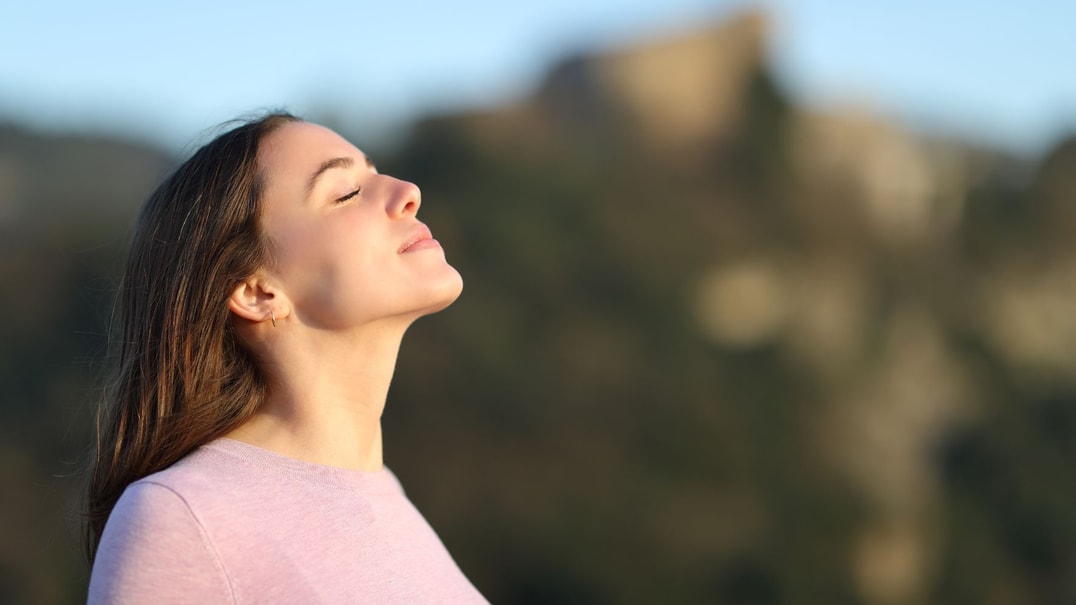 Person in pink top inhaling fresh mountain air