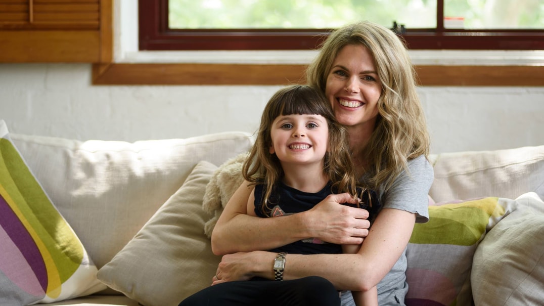 Emma poses with child on couch